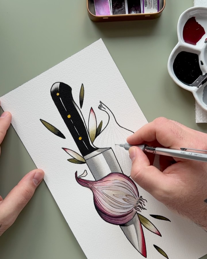 An artist's hand paints a chef's knife and red onion with olive green leaves and purple accents on white paper using watercolor.