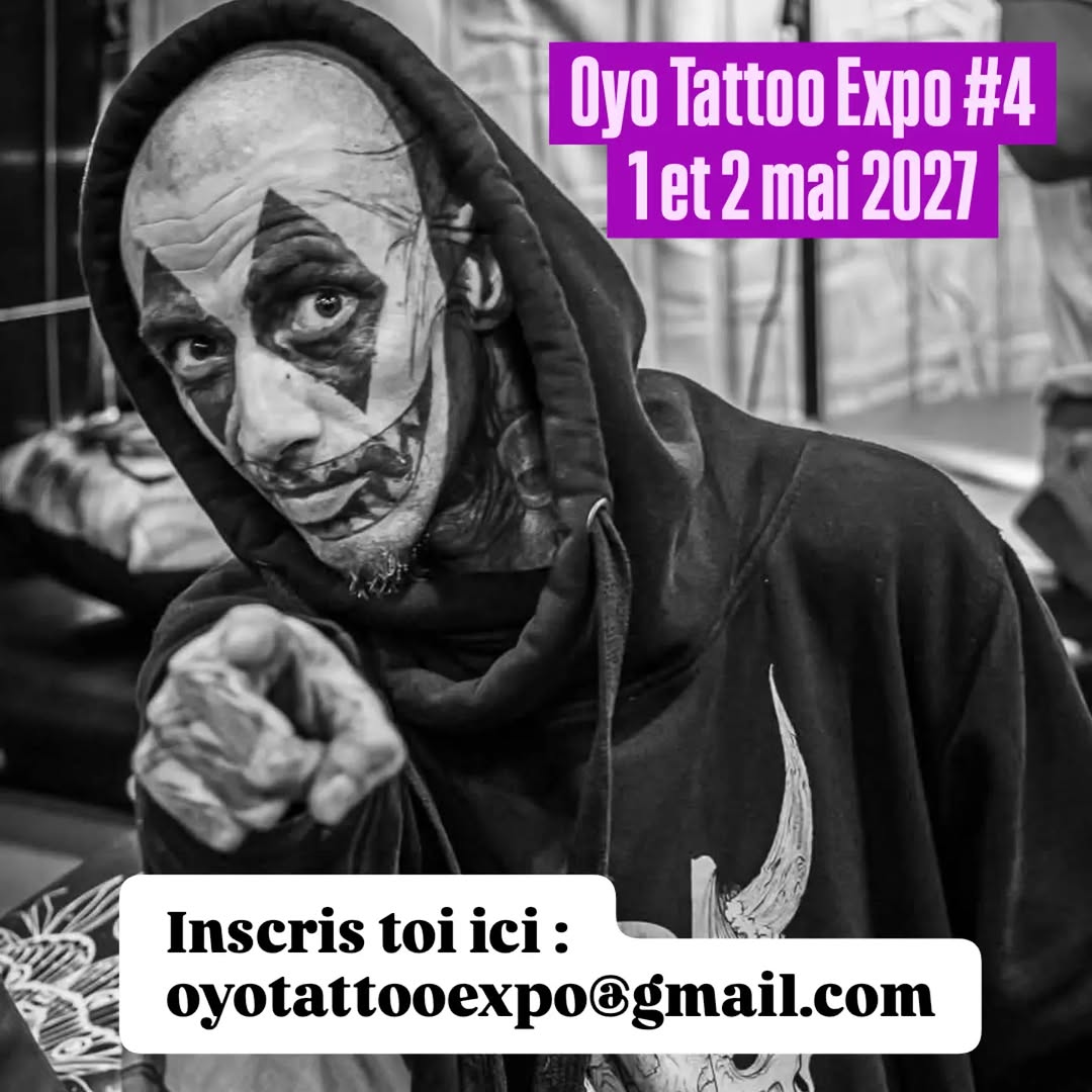Person wearing black hoodie with geometric face tattoo covering forehead and cheeks in black ink, pointing at camera.