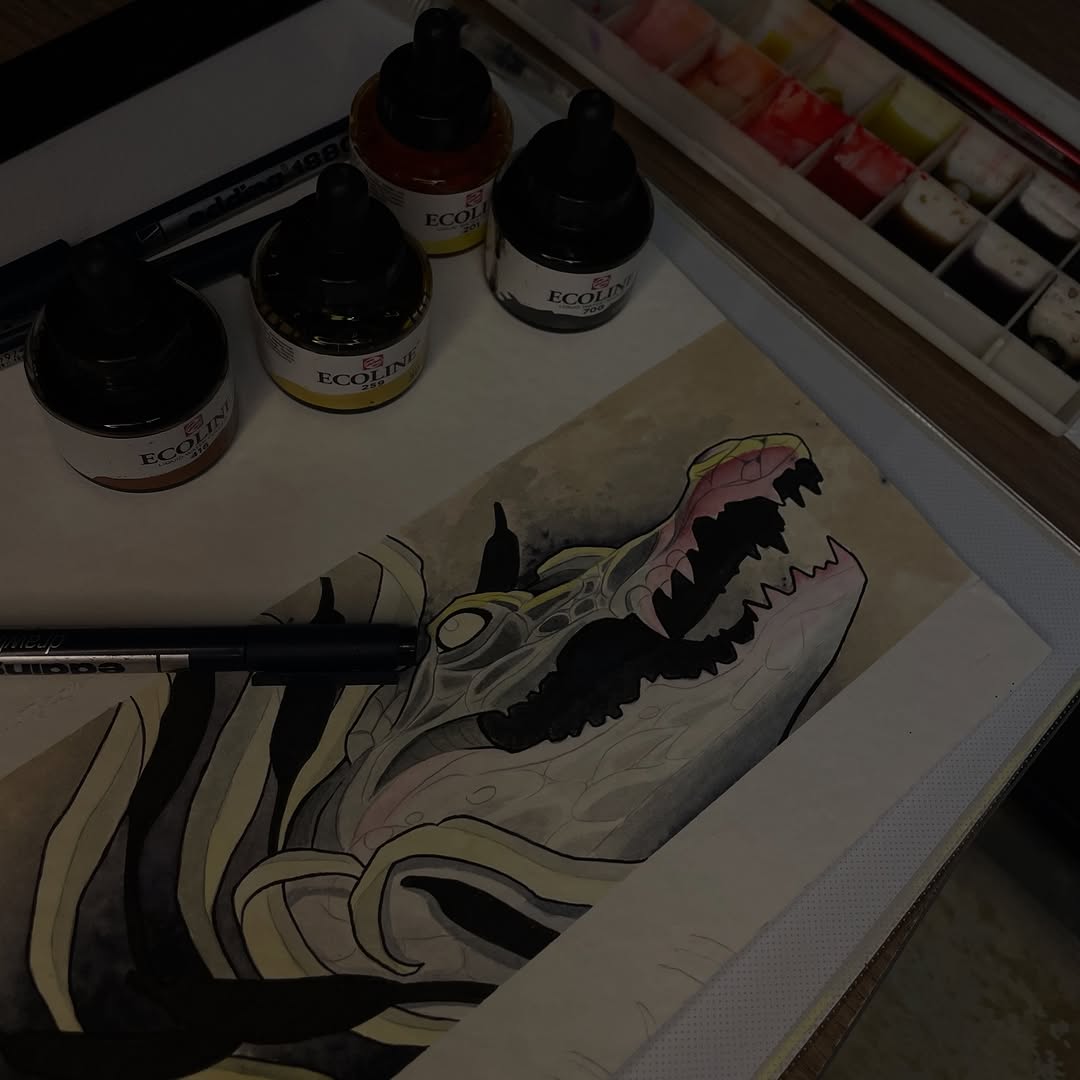 Detailed drawing of an open mouth with sharp teeth and pink interior, outlined in black ink with cream and yellow shading, on white paper with paint bottles nearby.