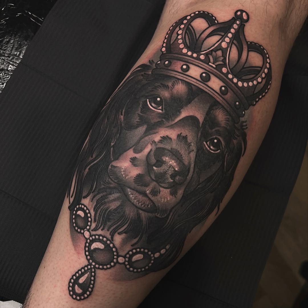 Crowned dog head with long ears and jeweled collar and earrings in black and pink ink on a forearm.