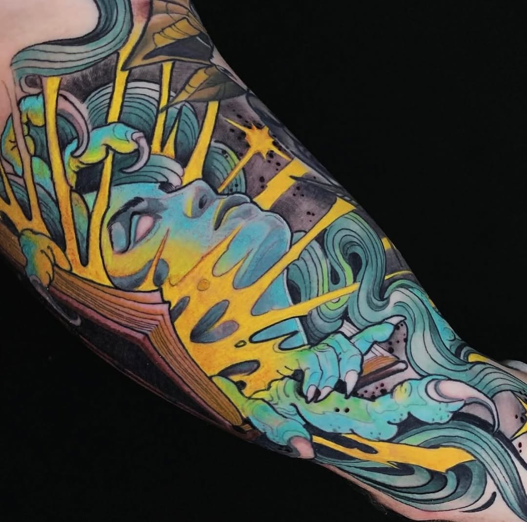 Colorful sleeve tattoo featuring a yellow and turquoise fish with decorative swirling patterns and ornamental elements in yellow, teal, and dark tones on the arm.