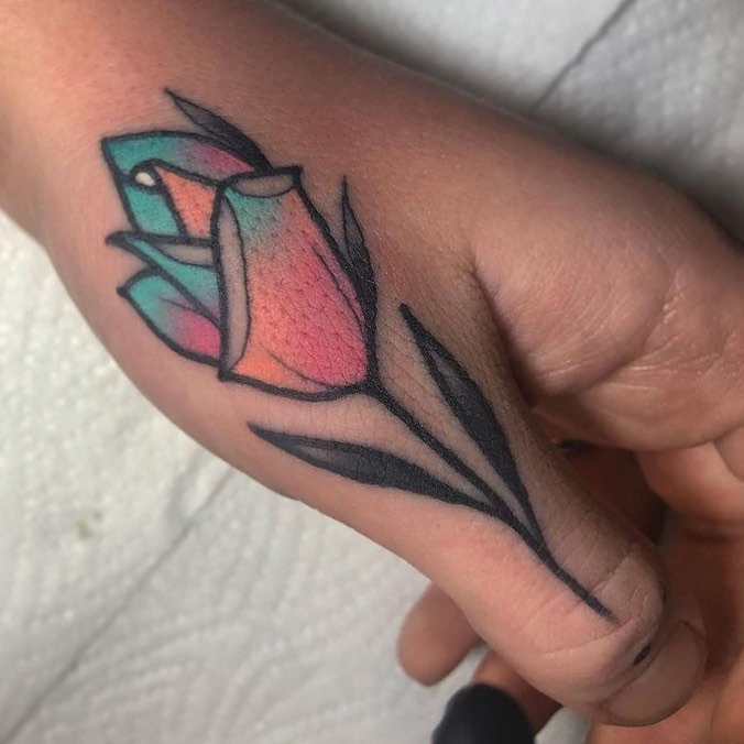 Geometric tulip tattoo with turquoise and pink coloring and black outline on the side of a hand.
