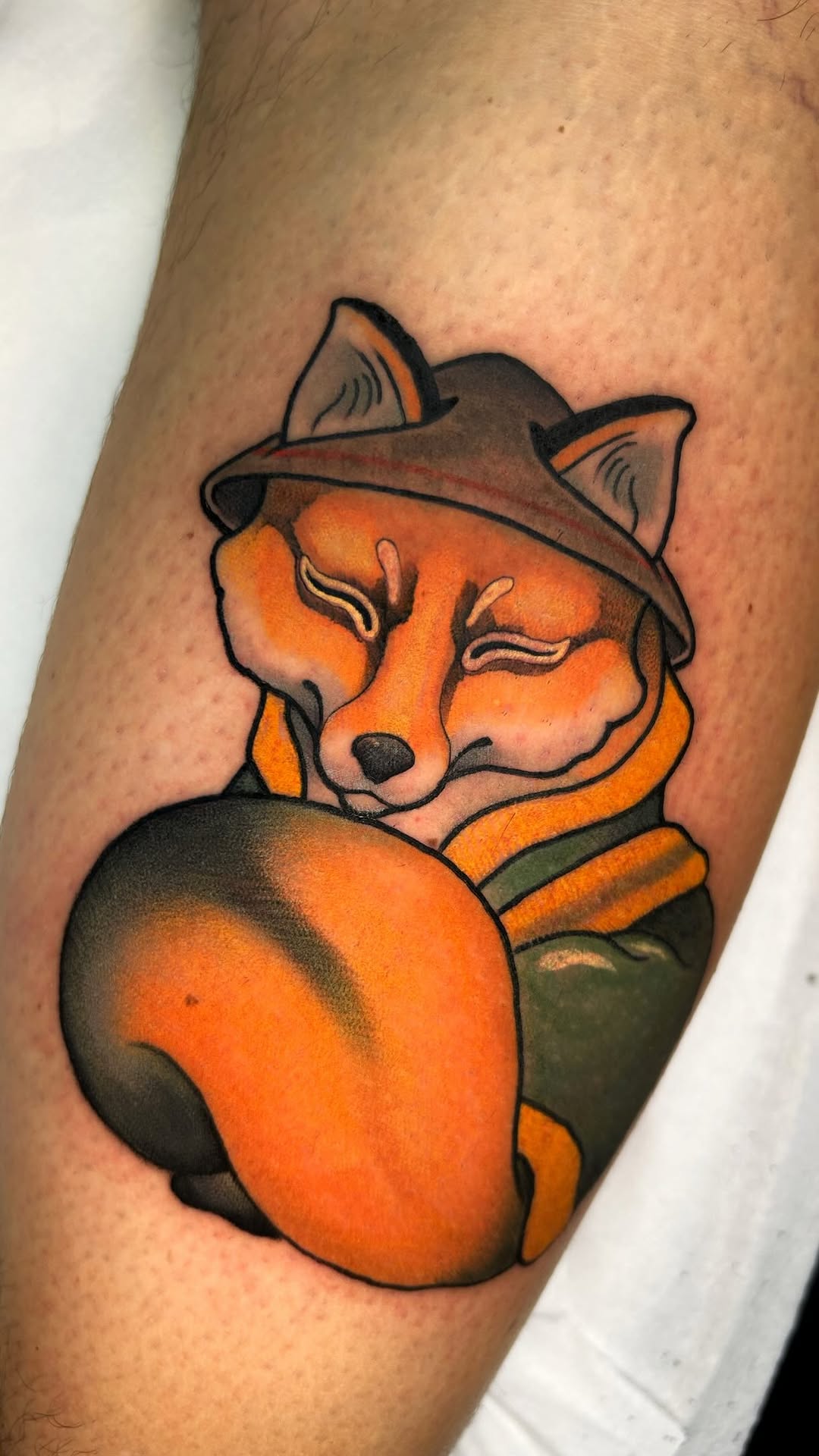 Fox wearing a cowboy hat and brown jacket on an upper arm, rendered in orange, brown, black, and green ink.