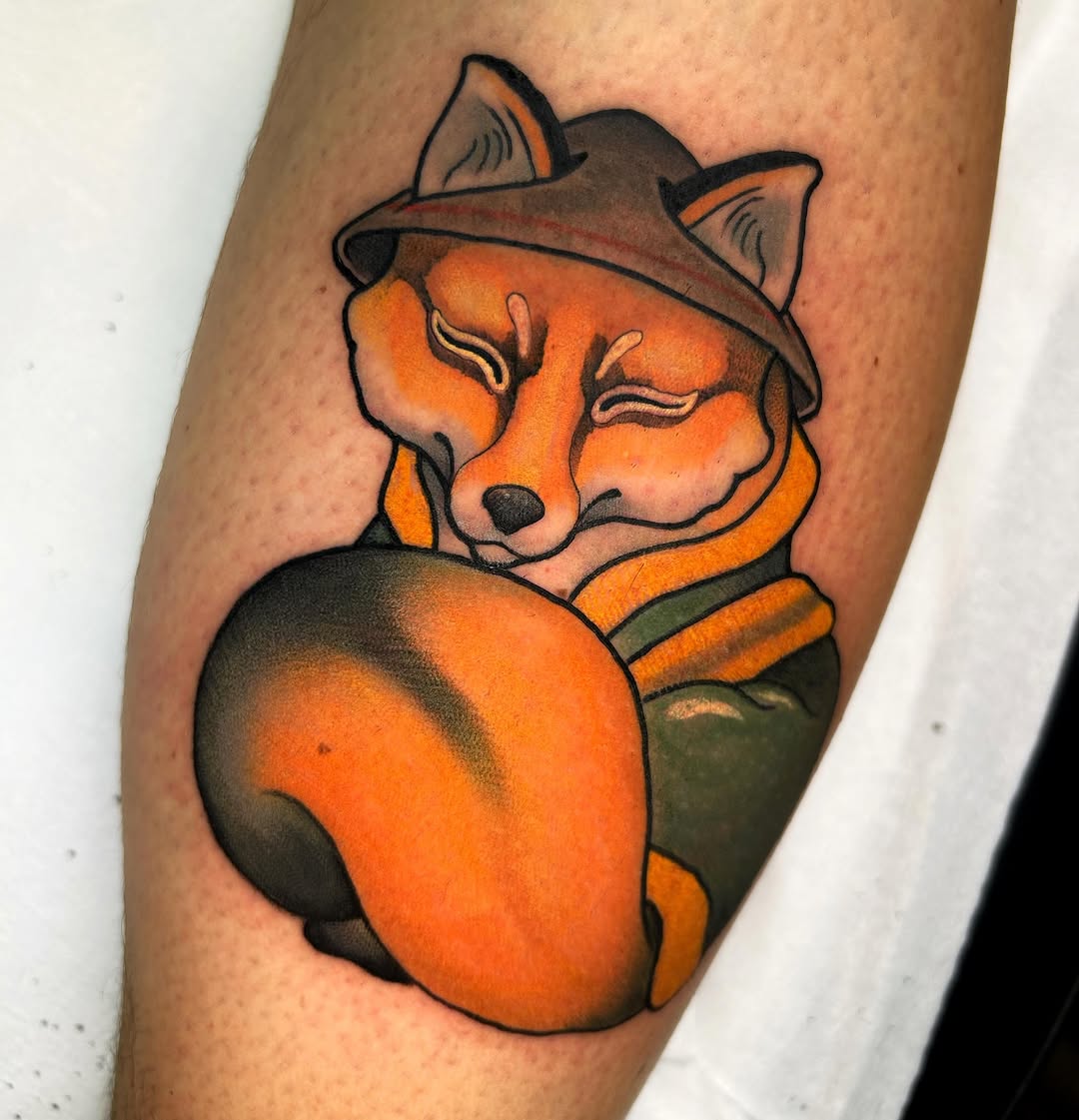 Colorful fox tattoo wearing a cowboy hat and green jacket on an arm, rendered in orange, brown, and black ink.