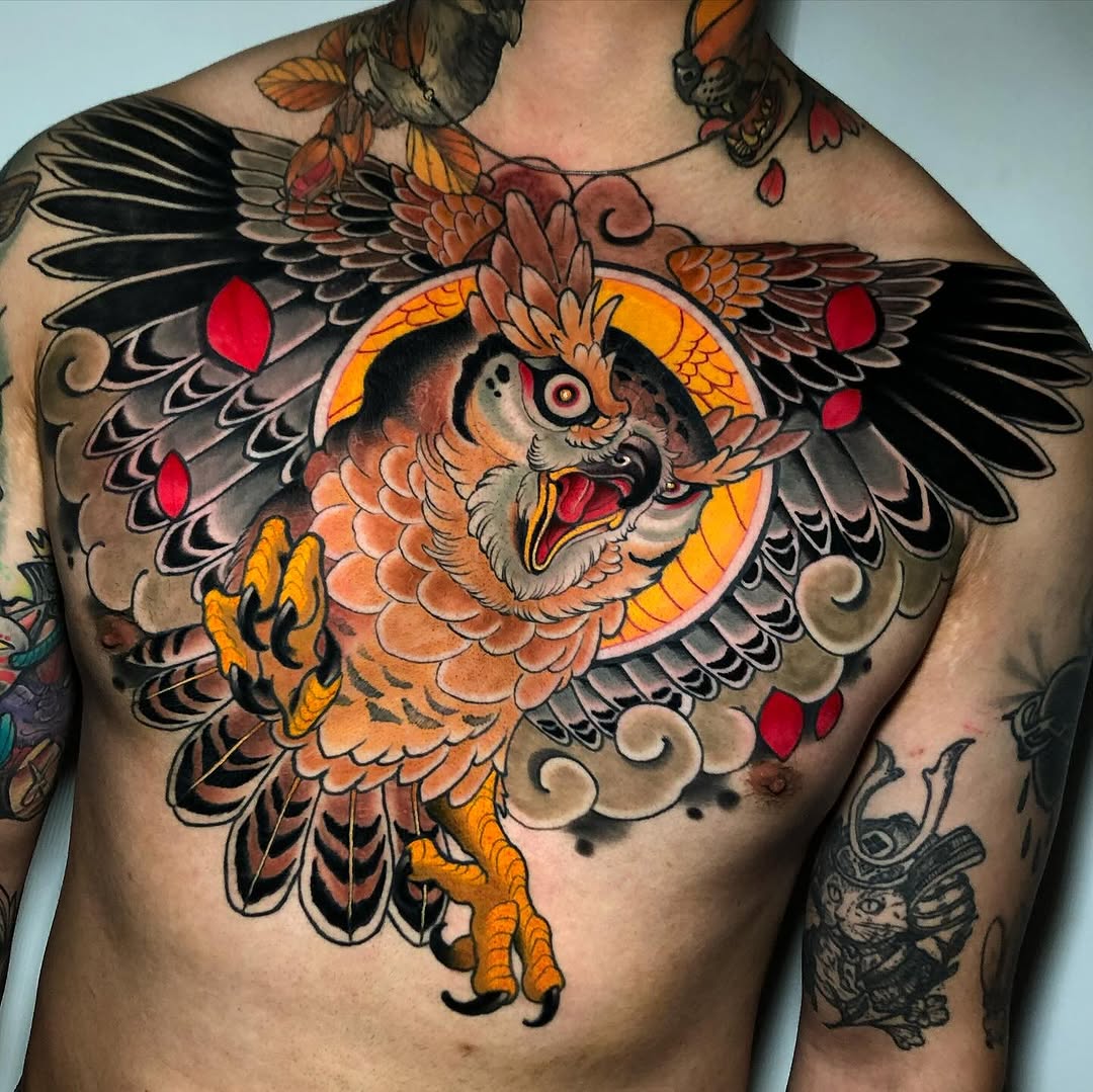 Colorful owl chest tattoo featuring orange and black wings, red details, yellow talons, and a glowing circular background on a shirtless male torso.