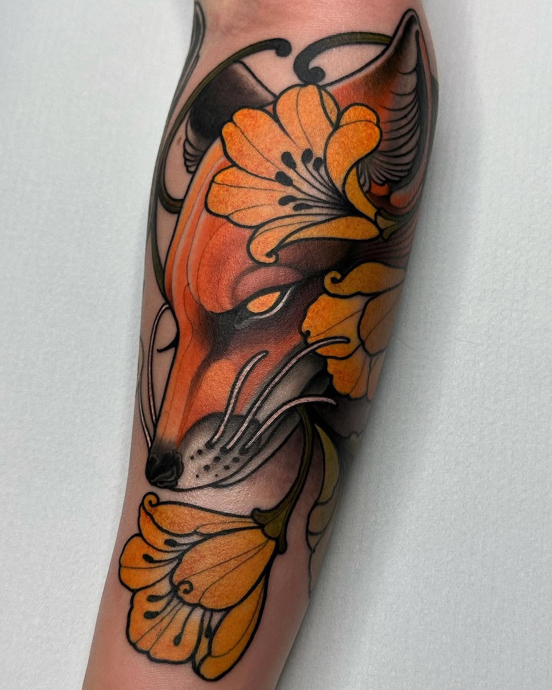 A colorful koi fish tattoo on the calf featuring orange and black shading with decorative floral elements below.