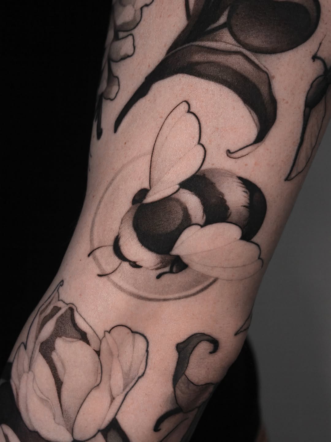 Tattoo on leg featuring Mickey Mouse character with large gloved hands and round ears, rendered in black and gray shading on skin.