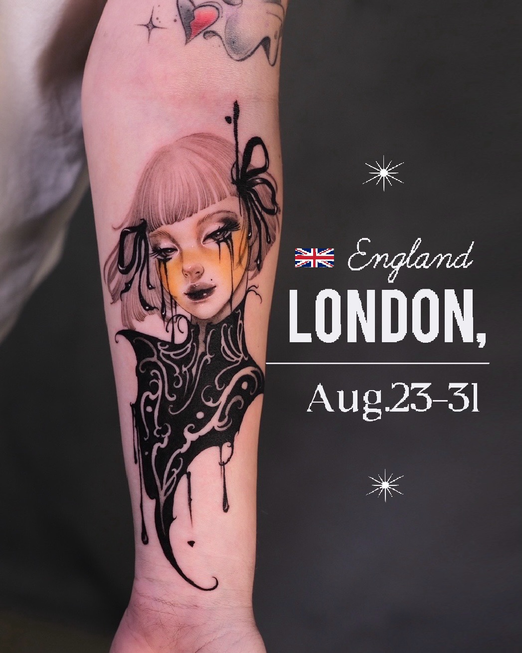 Colorful arm tattoo featuring an androgynous figure with bangs, ornate chest design, decorative elements, and heart motif in pink, yellow, and black ink.