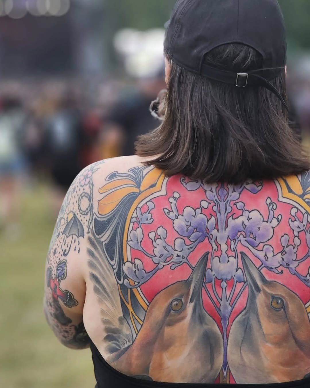 Back tattoo featuring two deer heads with ornate floral designs in red, purple, blue, and gold on bare skin.