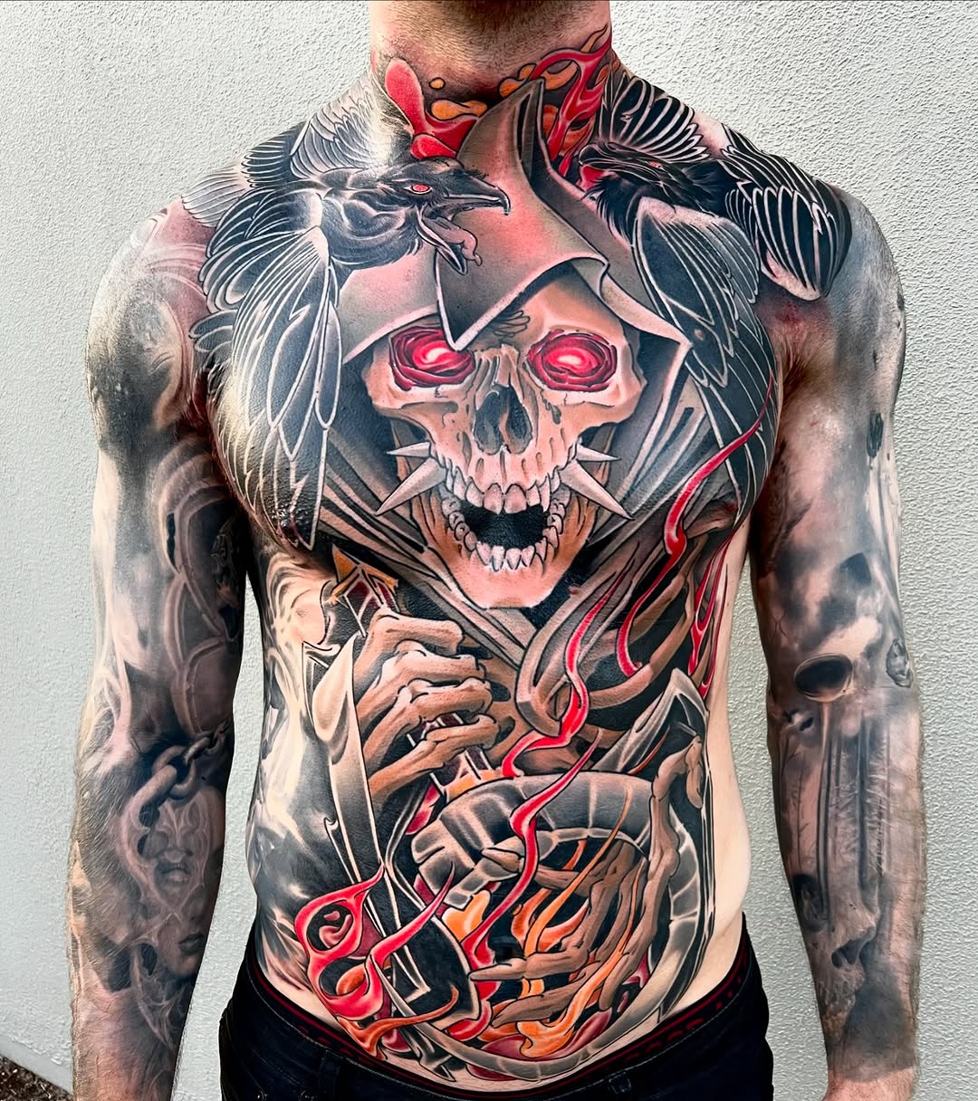 Large skull with glowing red eyes and black wings on chest, surrounded by red and orange flowing elements and skeletal hands on torso.