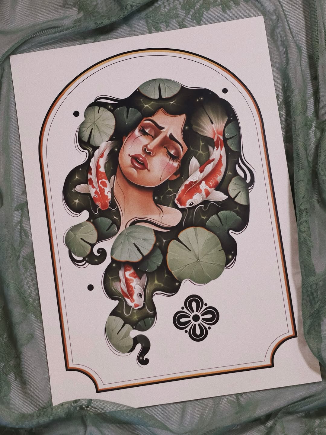 Tattoo design featuring a woman's face with red koi fish and lily pad leaves in an ornate frame with a floral symbol below.