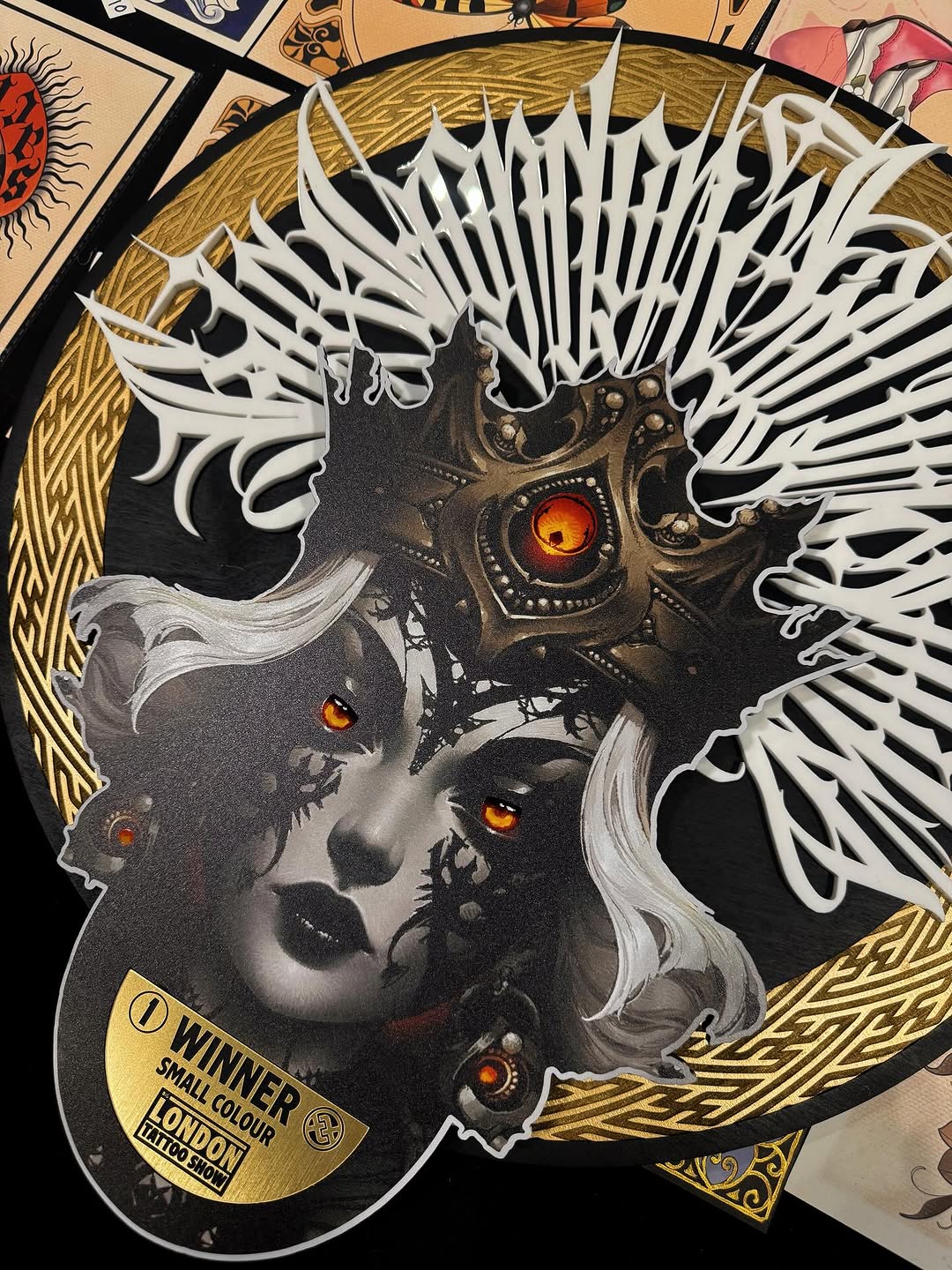 Detailed portrait tattoo featuring a face with mechanical steampunk elements, white feathered wings, and glowing amber eyes on the chest and shoulders.