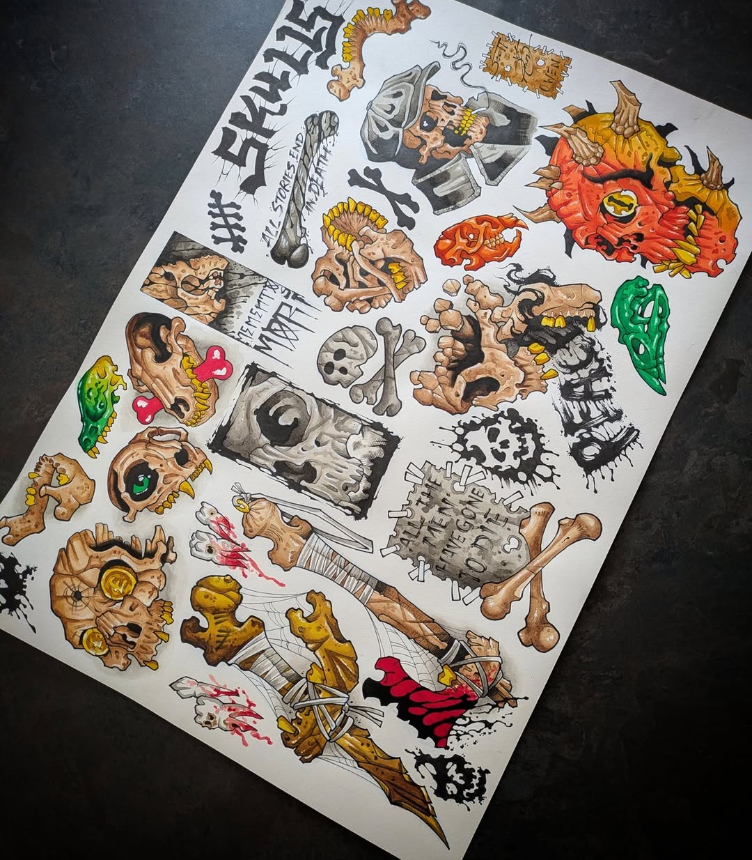 Tattoo flash sheet featuring colorful demon heads, skulls, bones, and monster designs in tan, red, yellow, green, and black ink on white paper.