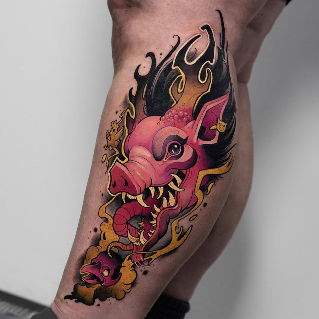 Colorful demon head tattoo on a calf featuring red, gold, and black hues with ornamental flames and decorative swirls.