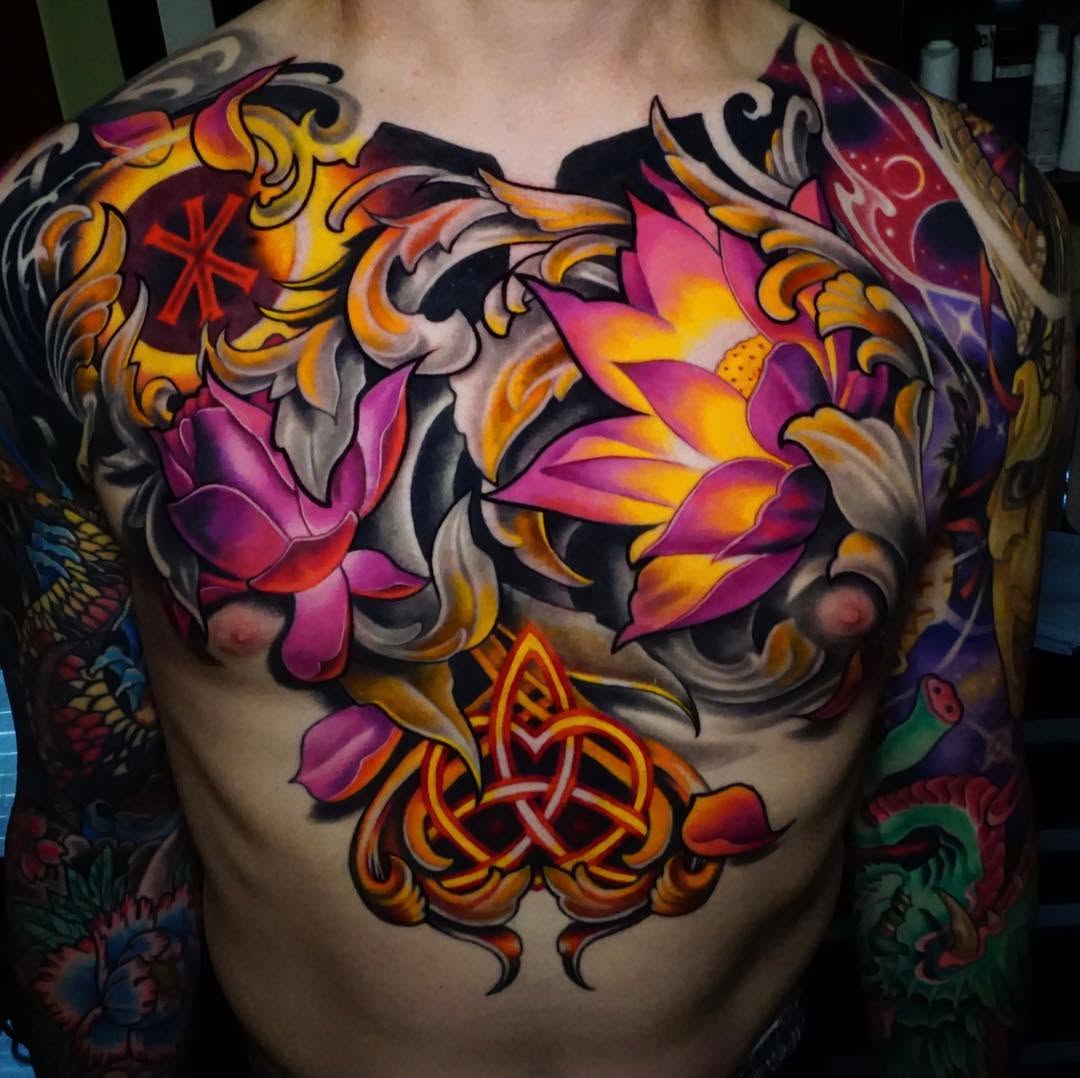 Colorful chest tattoo featuring pink and orange flowers with ornamental scrollwork and Celtic knotwork in gold and red tones.