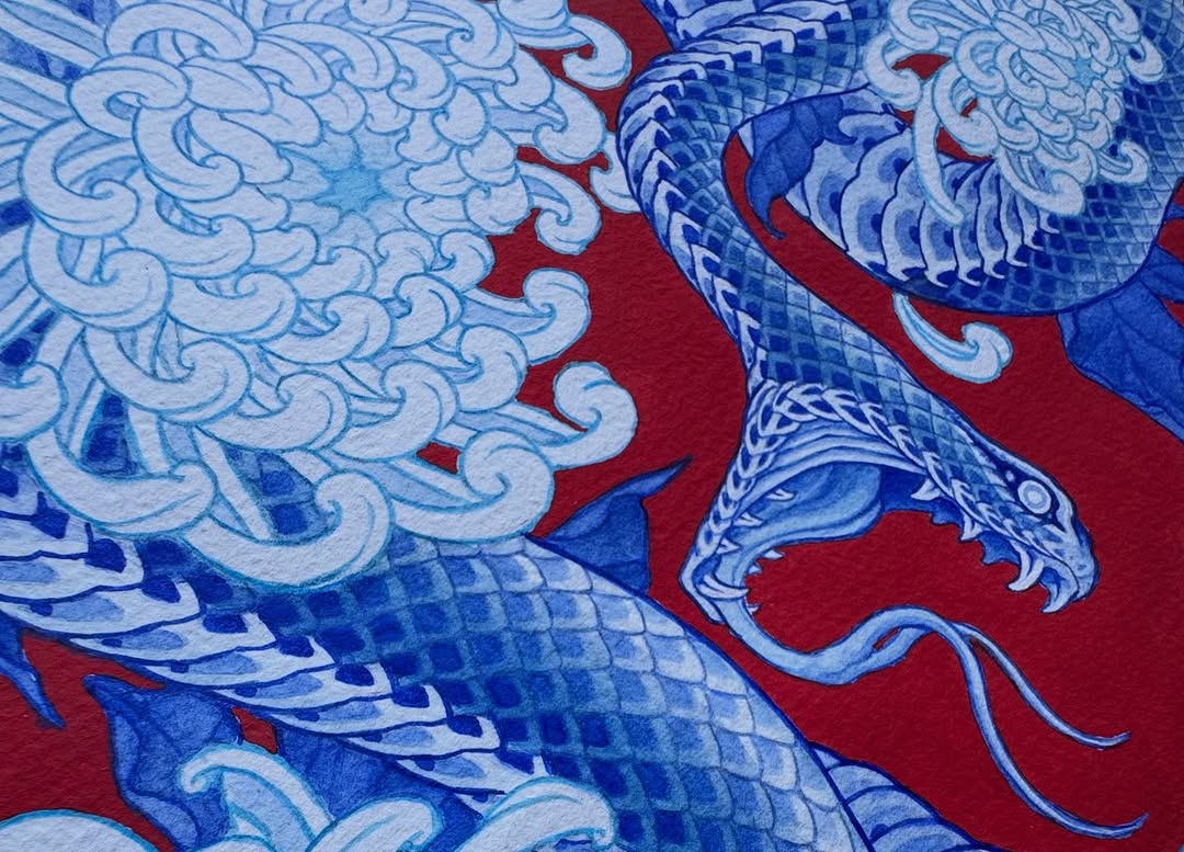 Blue and white dragon with ornate scaled wings and curled whiskers on red background fabric or paper.