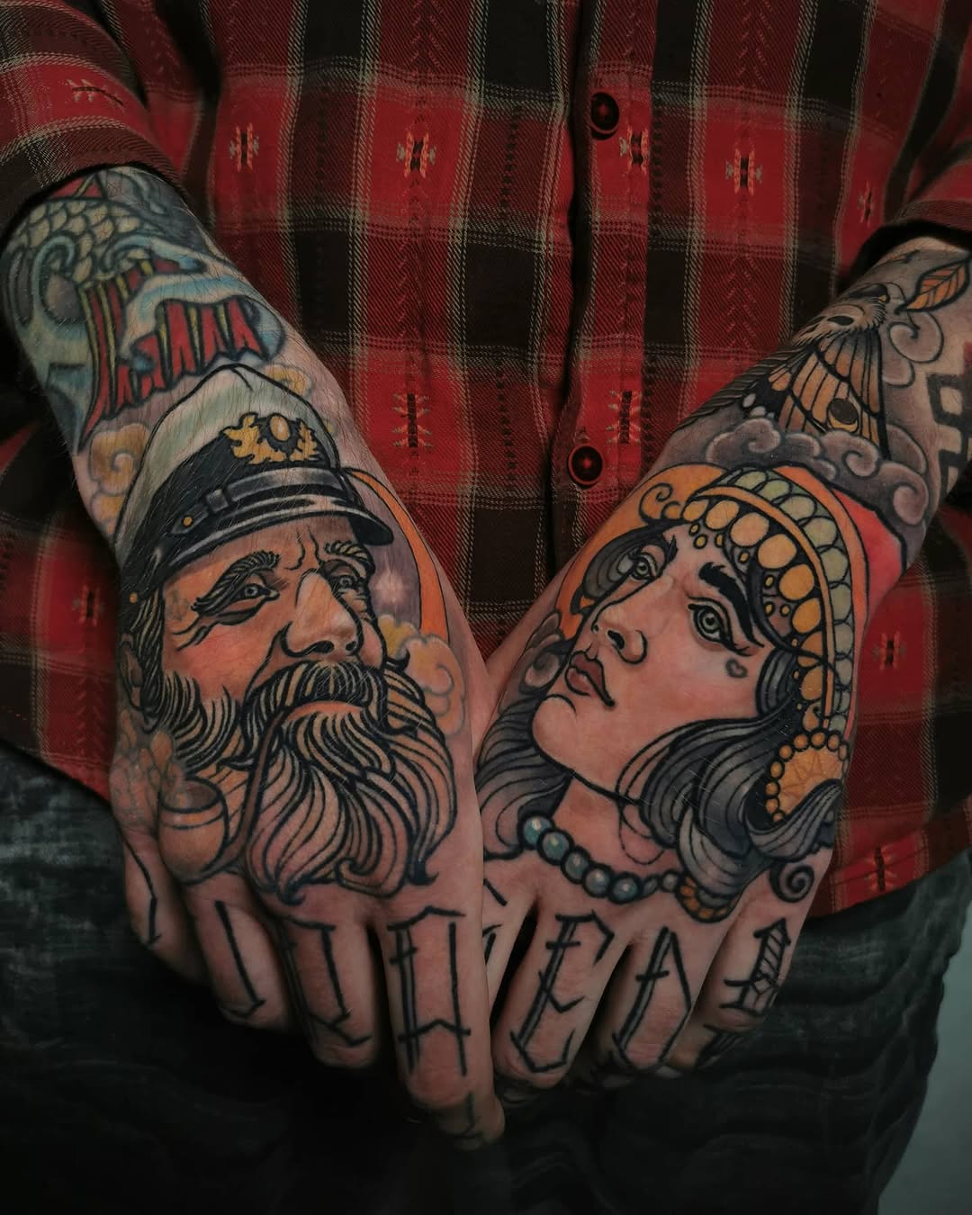 Two ornate portrait heads with jewelry and decorative elements tattooed on knuckles and hands in red, orange, black, and skin tones.