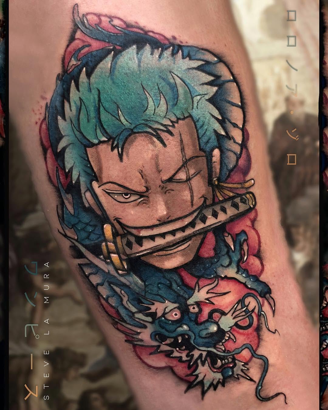 Colorful tattoo on upper arm featuring a character with teal hair and closed eyes, a decorative mouth piece, and a demon creature below in pink and blue tones.