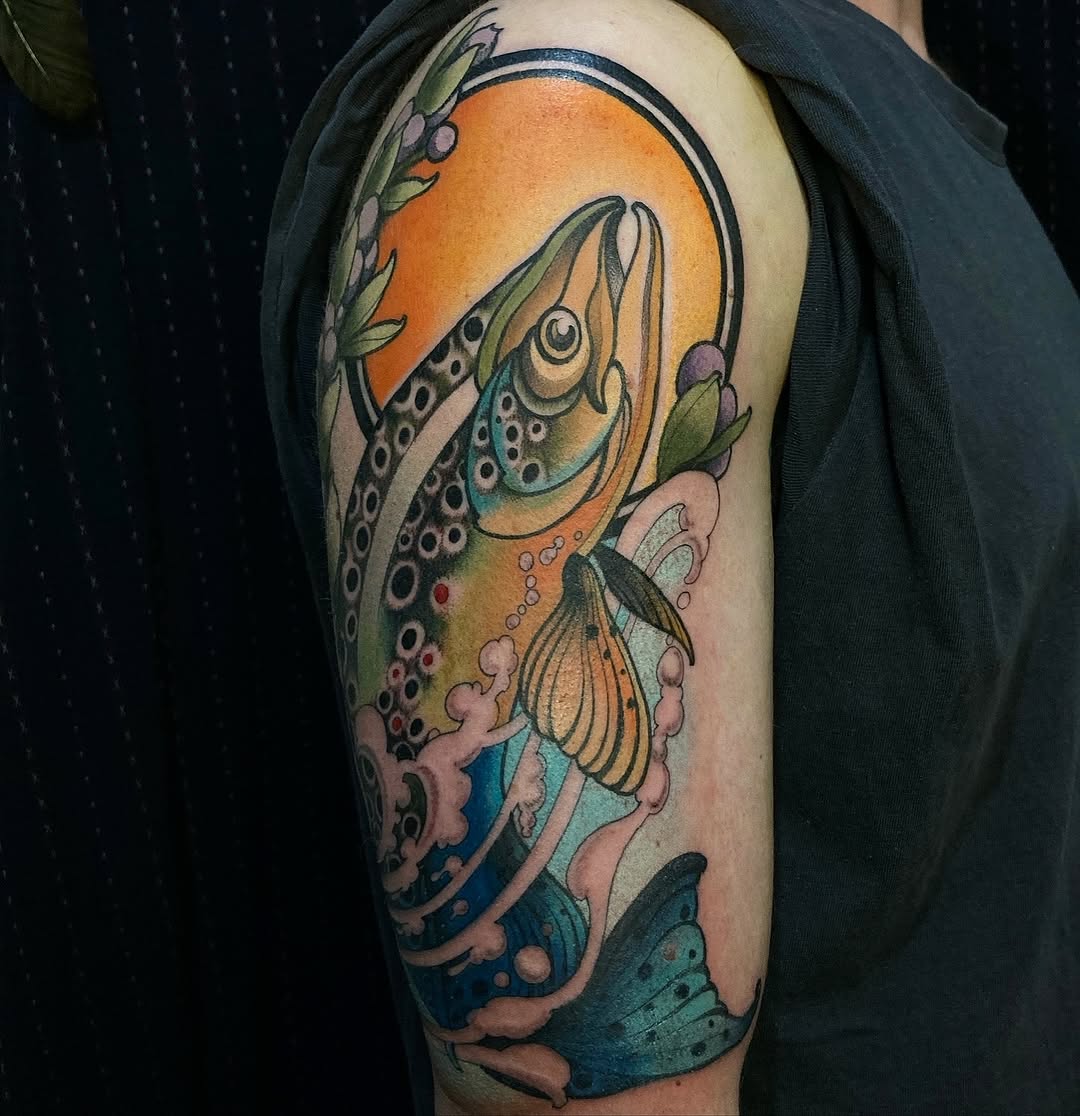 Colorful trout tattoo on upper arm featuring green, orange, and blue hues with detailed spotting and water elements surrounding the fish.