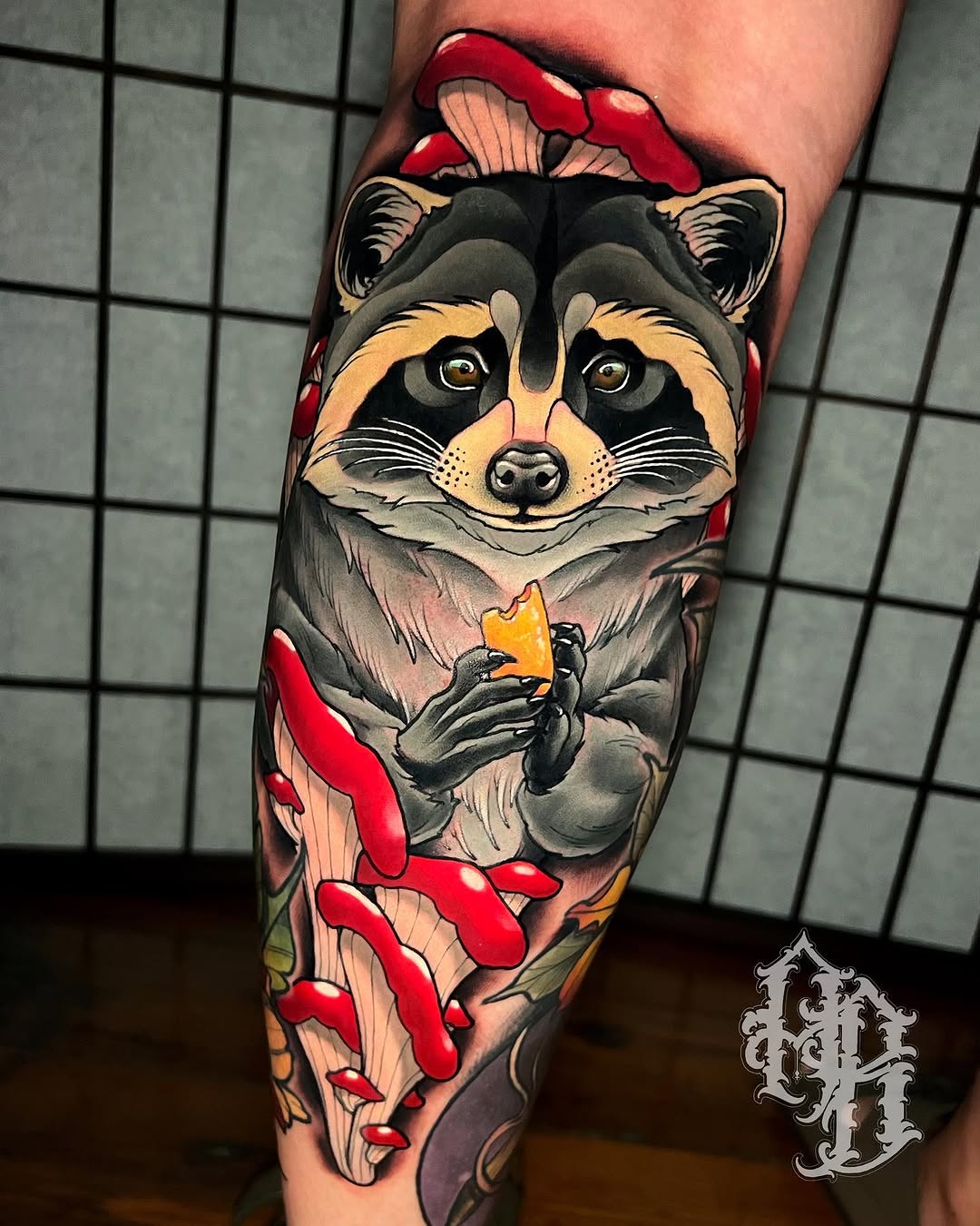 Colorful raccoon tattoo on the calf holding cheese, surrounded by red mushrooms and yellow flowers, with gold eyes and detailed shading.
