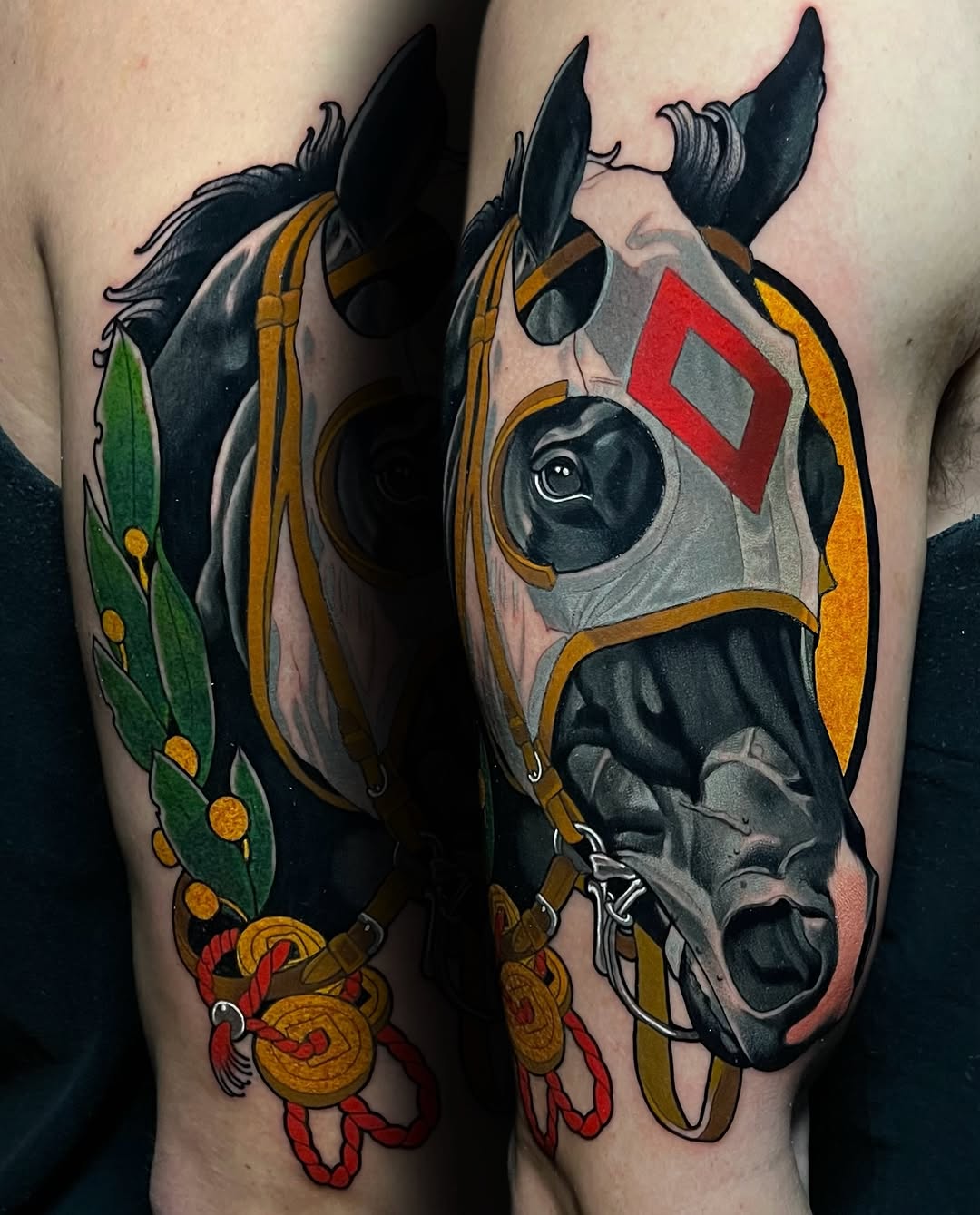 Detailed horse head tattoo with gold tack, red diamond marking, green laurel wreath, and decorative red ribbons on upper arm.