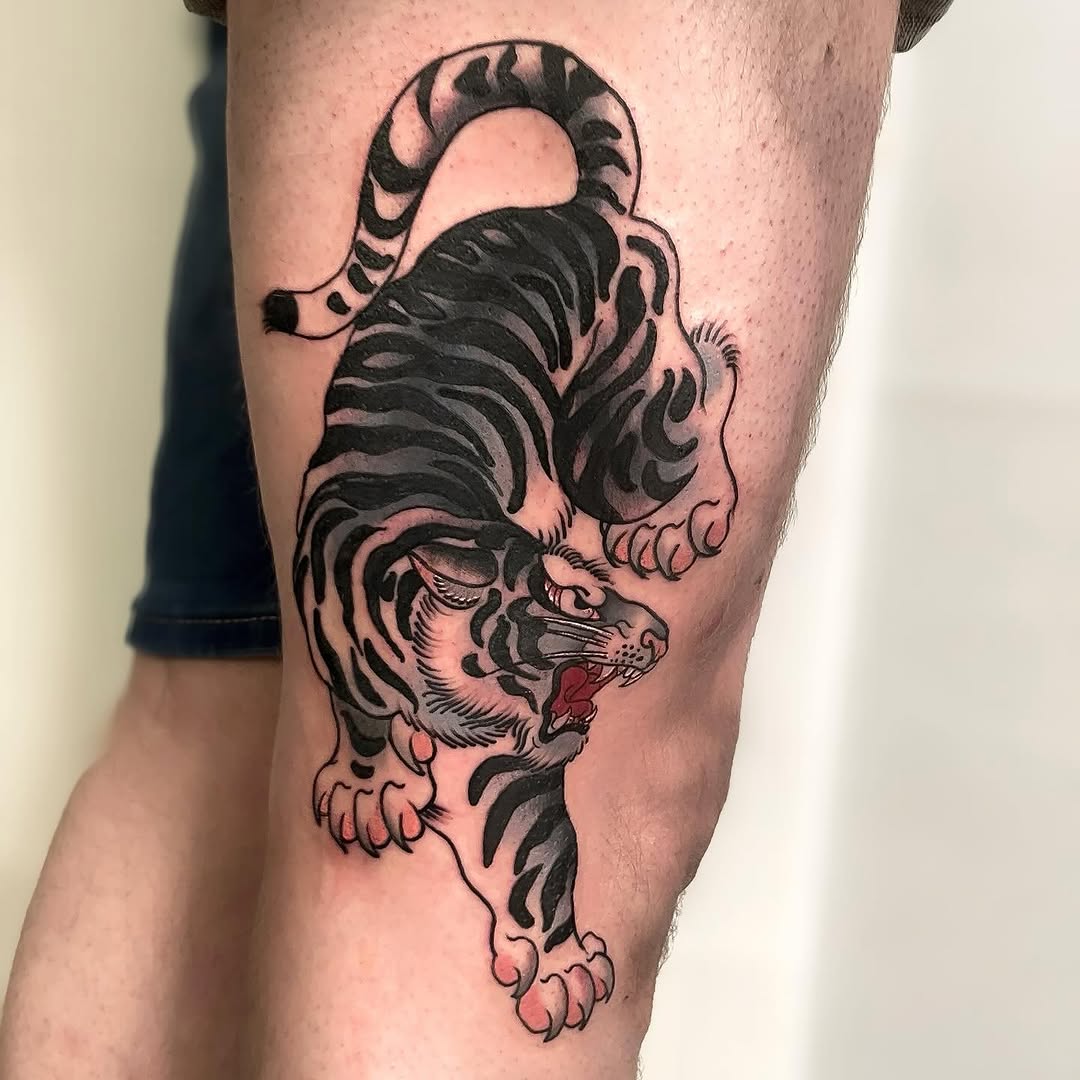 Two tigers stacked vertically on a thigh, rendered in black ink with red accents in the mouth, showing detailed stripes and facial features.