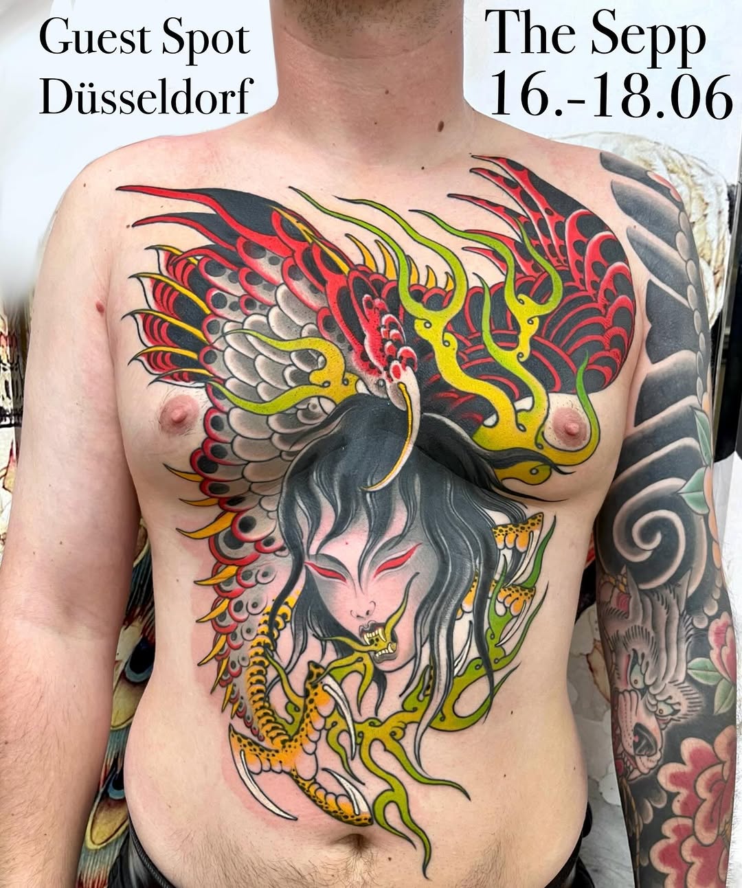 Colorful chest tattoo featuring a demon face with grey hair, yellow horns, red and black wings, and green serpentine elements across the torso.