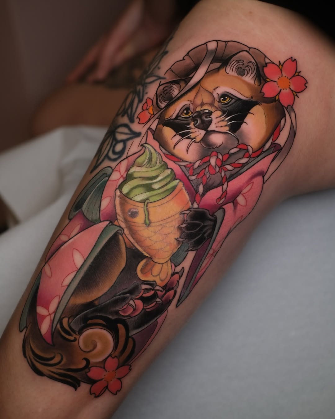 Colorful arm tattoo featuring two foxes with flowers in their hair, holding an ice cream cone, surrounded by red flowers and decorative swirls.