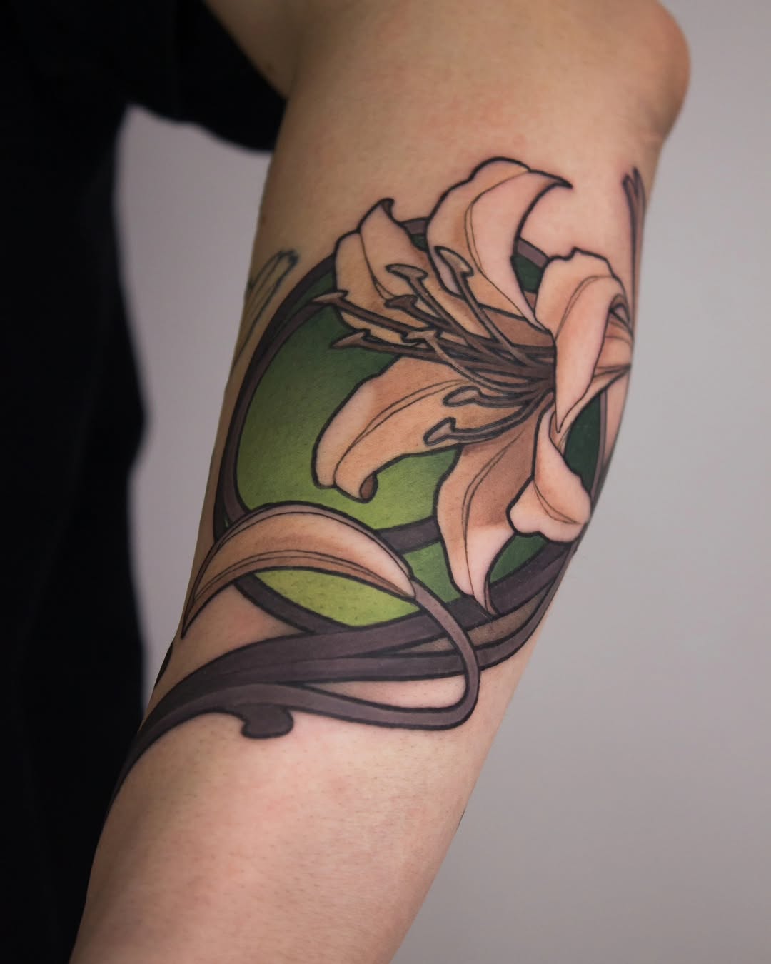 Floral tattoo on the upper arm featuring pink and peach petals with green leaves and dark brown stems and vines.