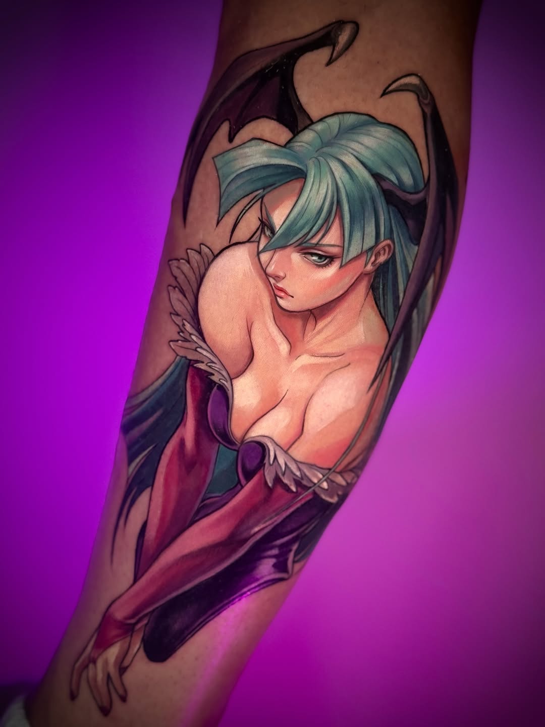 Colorful arm tattoo featuring a woman with teal hair and wings, rendered in purple, pink, and red tones against a glowing background.