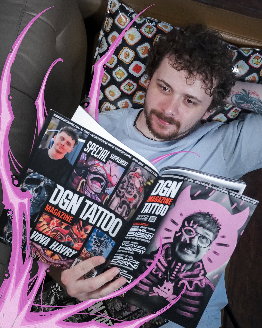 Man with dark curly hair holding DGN Tattoo Magazine featuring colorful skull and portrait designs in pink, black, and orange on the cover.