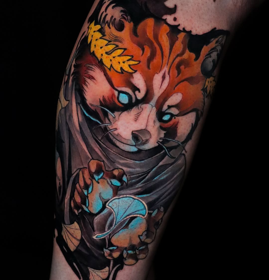 Colorful fox tattoo on thigh featuring orange flames, yellow crown, blue eyes, and paw pad detail on the leg.