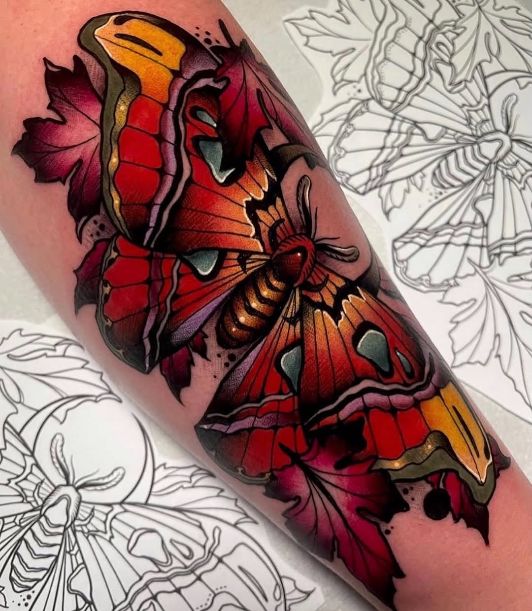 Colorful butterfly and floral tattoo on forearm featuring red, orange, purple, and yellow hues with detailed wings and leaves.
