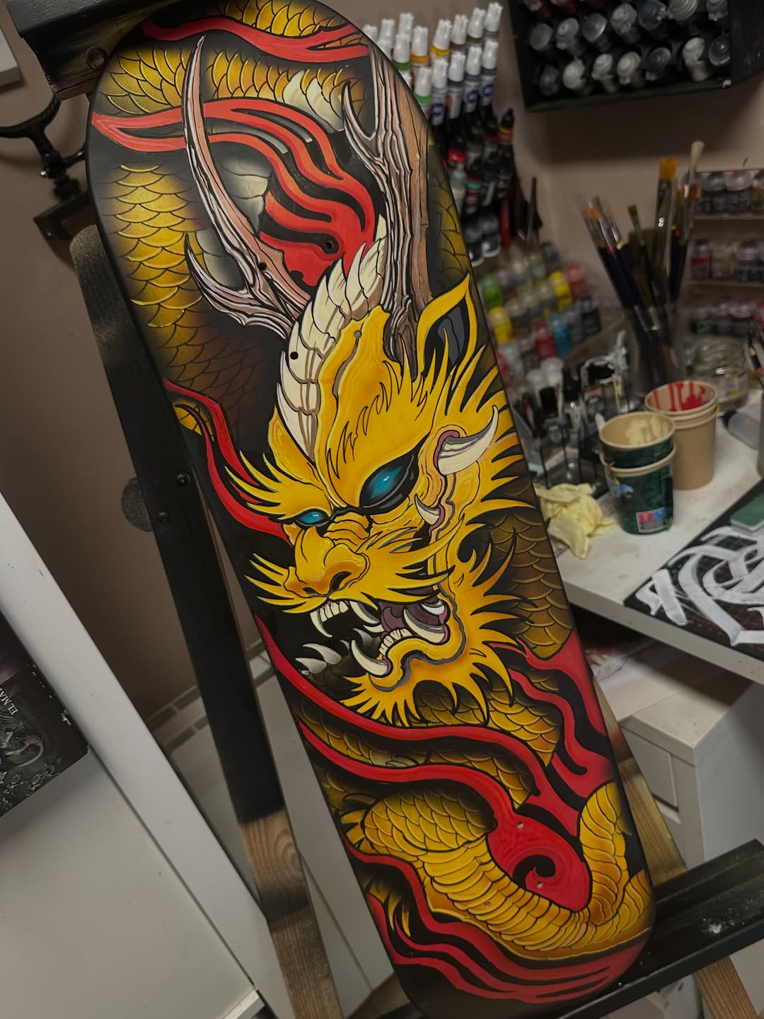 Colorful dragon tattoo design on black background featuring yellow scales, red flowing elements, and detailed facial features with blue eyes.