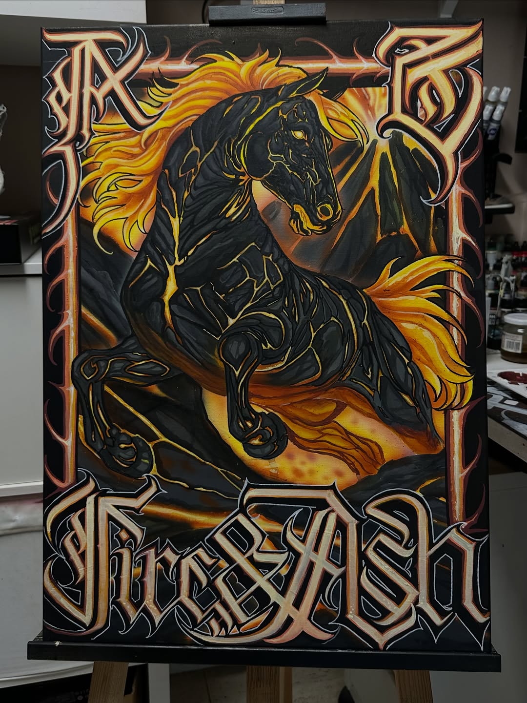 Black horse with golden mane and tail rearing in flames, surrounded by ornate Celtic knotwork border on canvas panel.